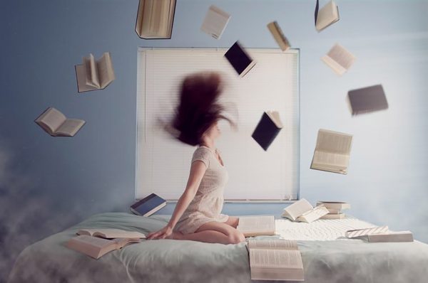 ベッドの上で本を投げ出す女性